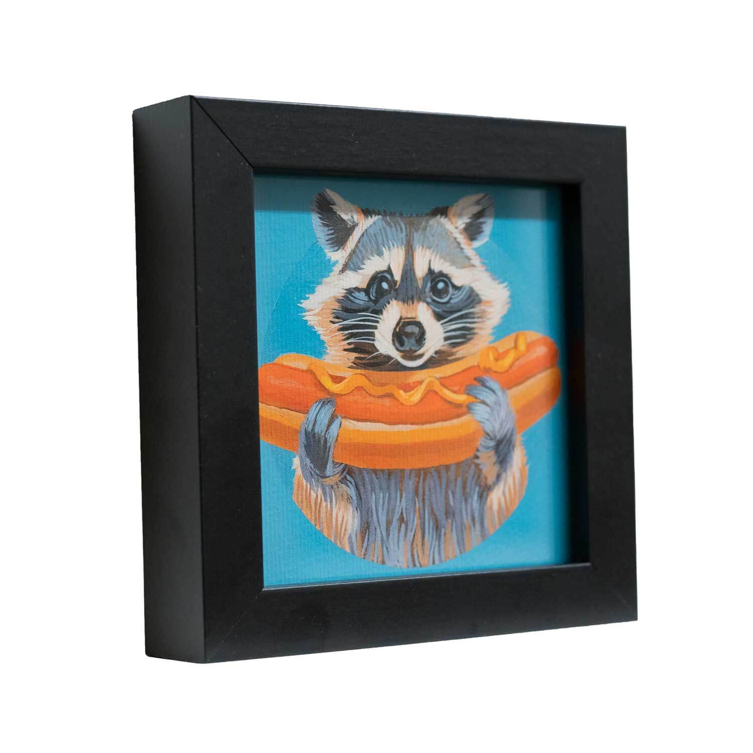 Cute raccoon holding a hot dog in a stylish black frame, perfect for decorating any space.