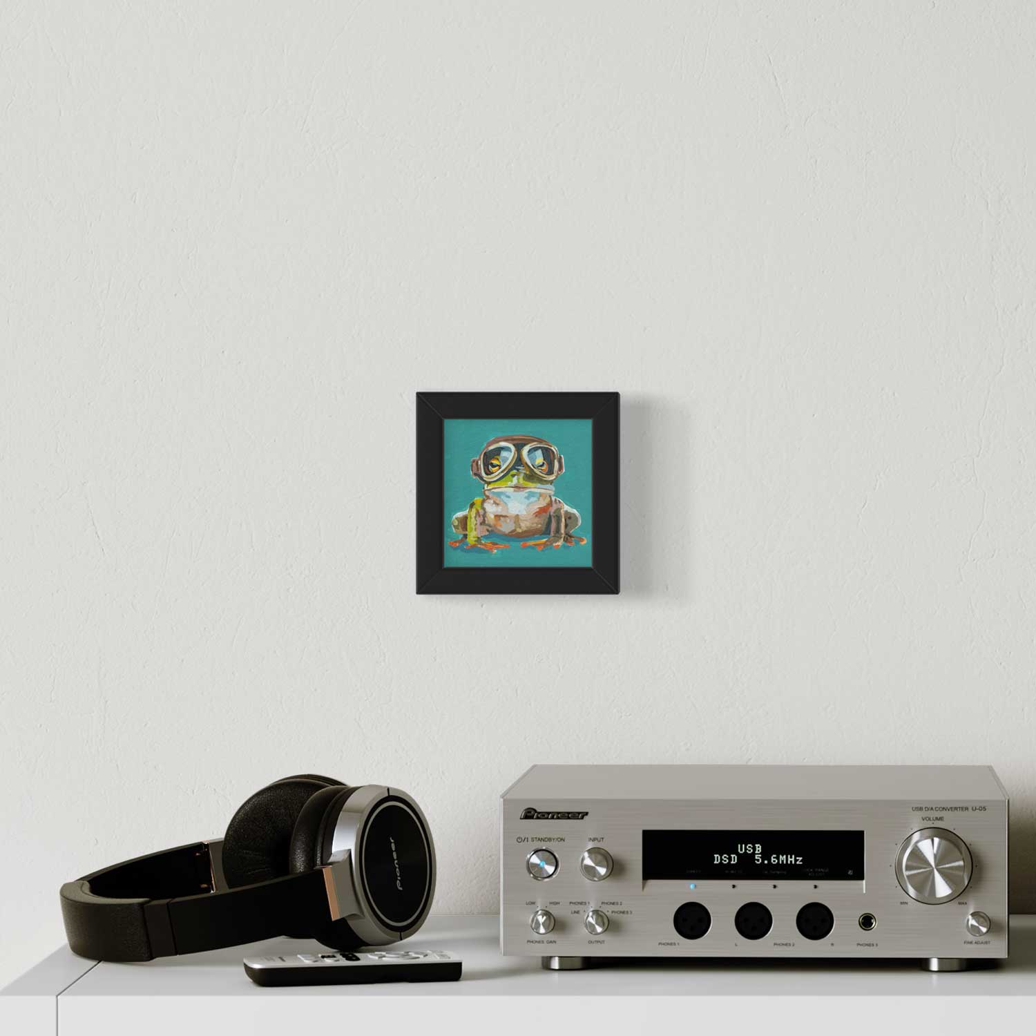 Cute adventurer frog art print in a trendy frame, adding charm to a stylish home audio setup.