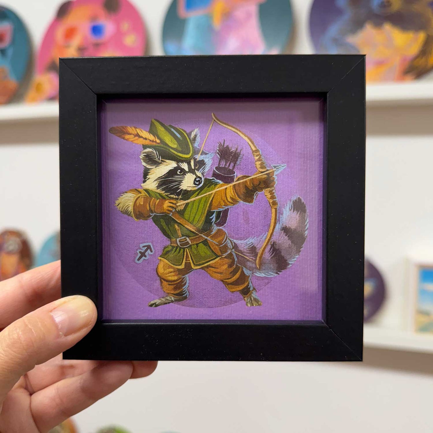 Cute raccoon archer in a 10x10 cm frame, bringing charm to any space as part of zodiac print collection.