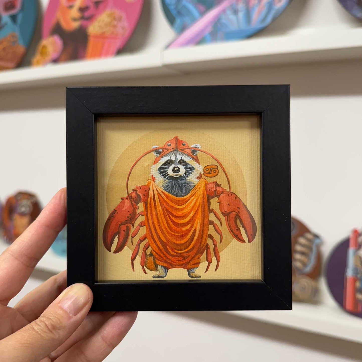 Cute raccoon dressed as a crab in a black frame, 10x10 cm, perfect for brightening up any space.