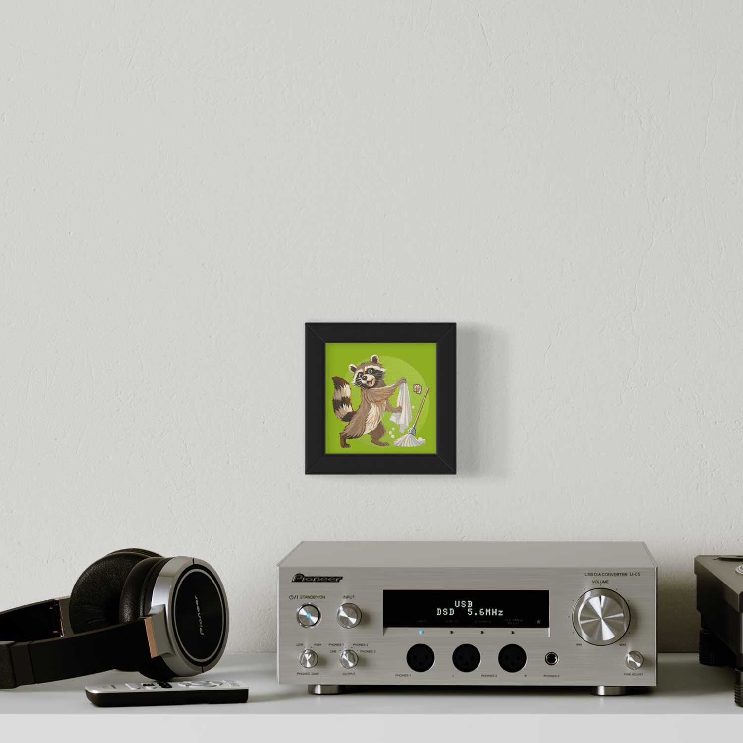 Cute raccoon art print framed in black, brightening a stylish room with a modern audio setup.