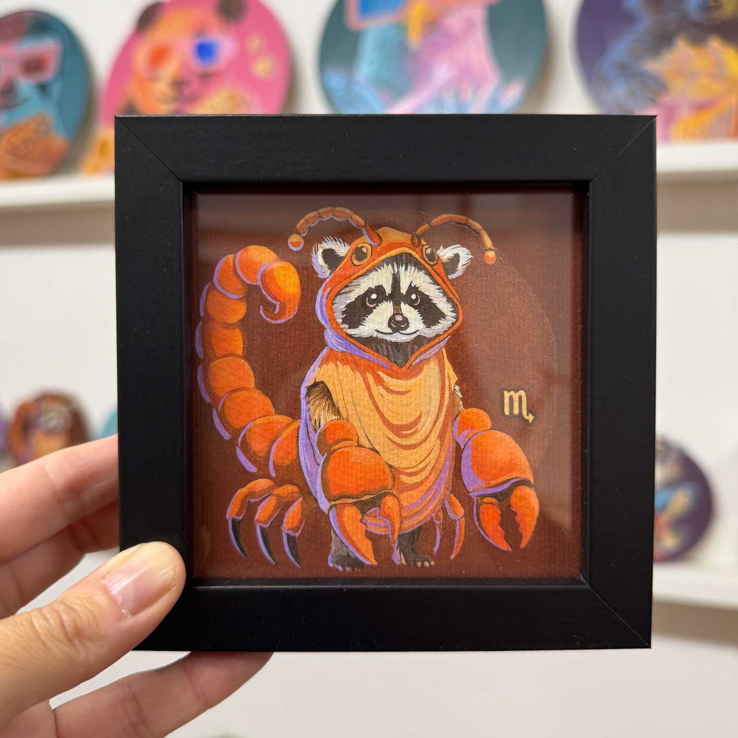 Cute raccoon dressed as a scorpion in a stylish black frame, perfect for adding charm to any space.