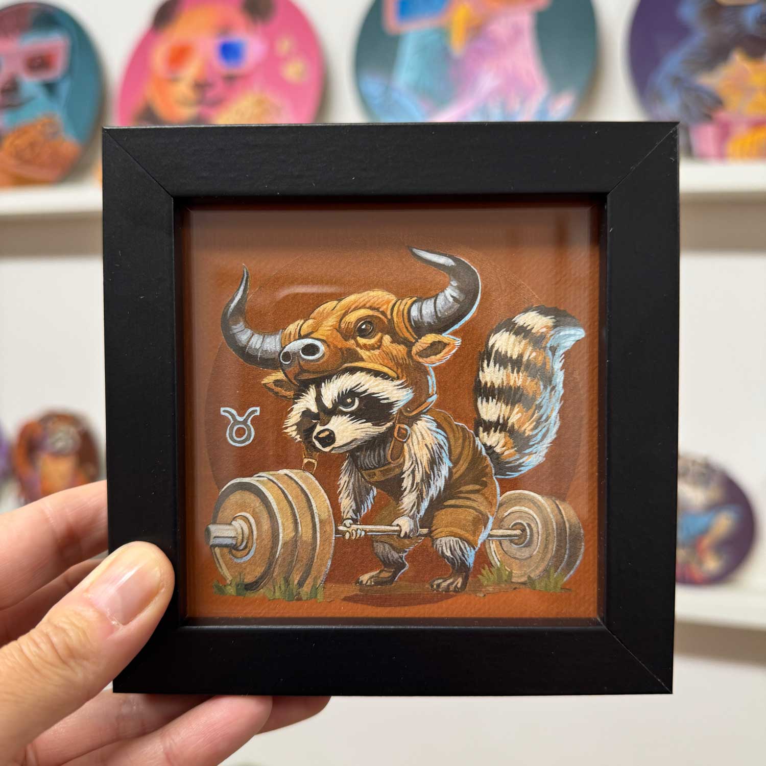 Cute raccoon lifting weights in a bull costume, framed art print for Taurus zodiac sign, perfect for home decor.