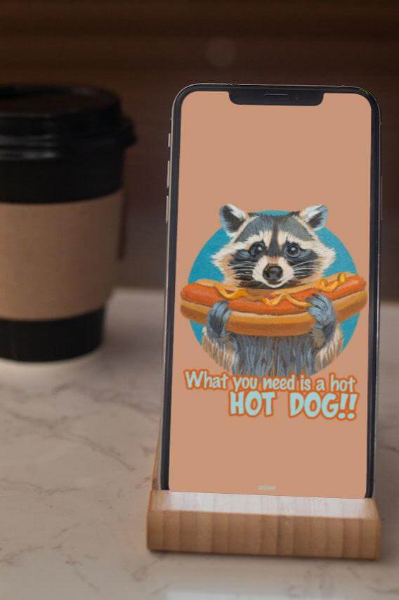 Smartphone mit Waschbär-Hintergrund: "What you need is a hot HOT DOG!!" in Pixel-Format 1080 x 1920, neben Kaffeebecher.